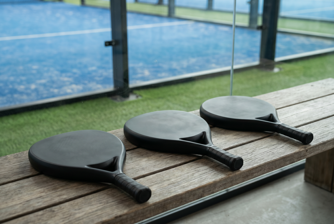 Drei Padel-Schläger verschiedener Formen auf der Bank – Spielstil wählen