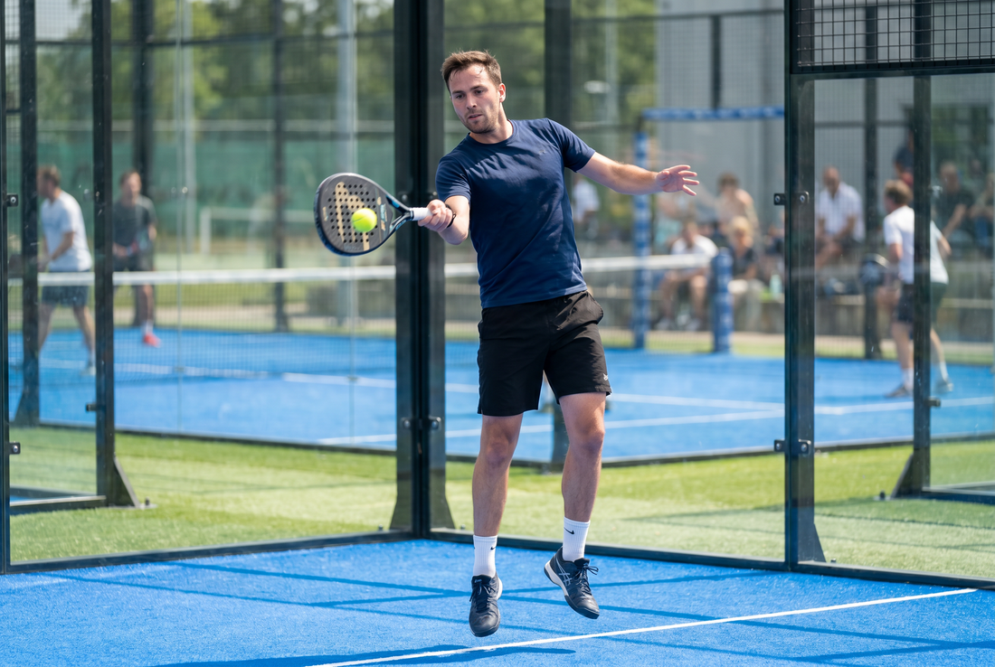 Fortgeschrittener Padelspieler beim Vorhand-Drive auf dem Court
